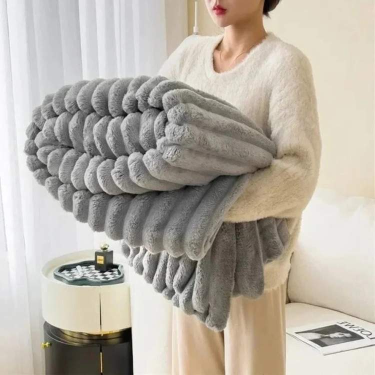 Faux-fur throw blanket in light gray with a striped design, styled on a bed
