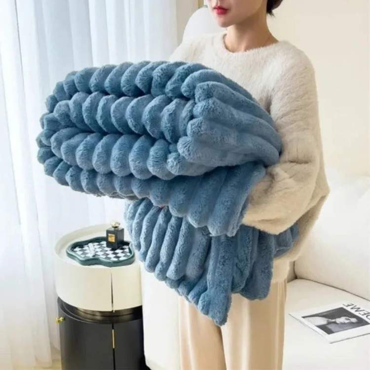 Faux-fur throw blanket in blue with a striped design, draped over an armchair