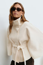 Cape-sleeve belted high-collar coat in beige.