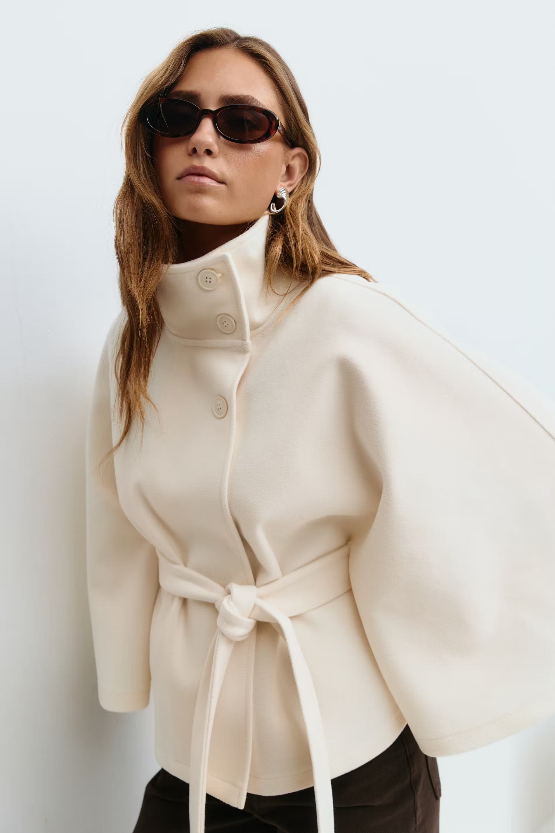 Cape-sleeve belted high-collar coat in beige.