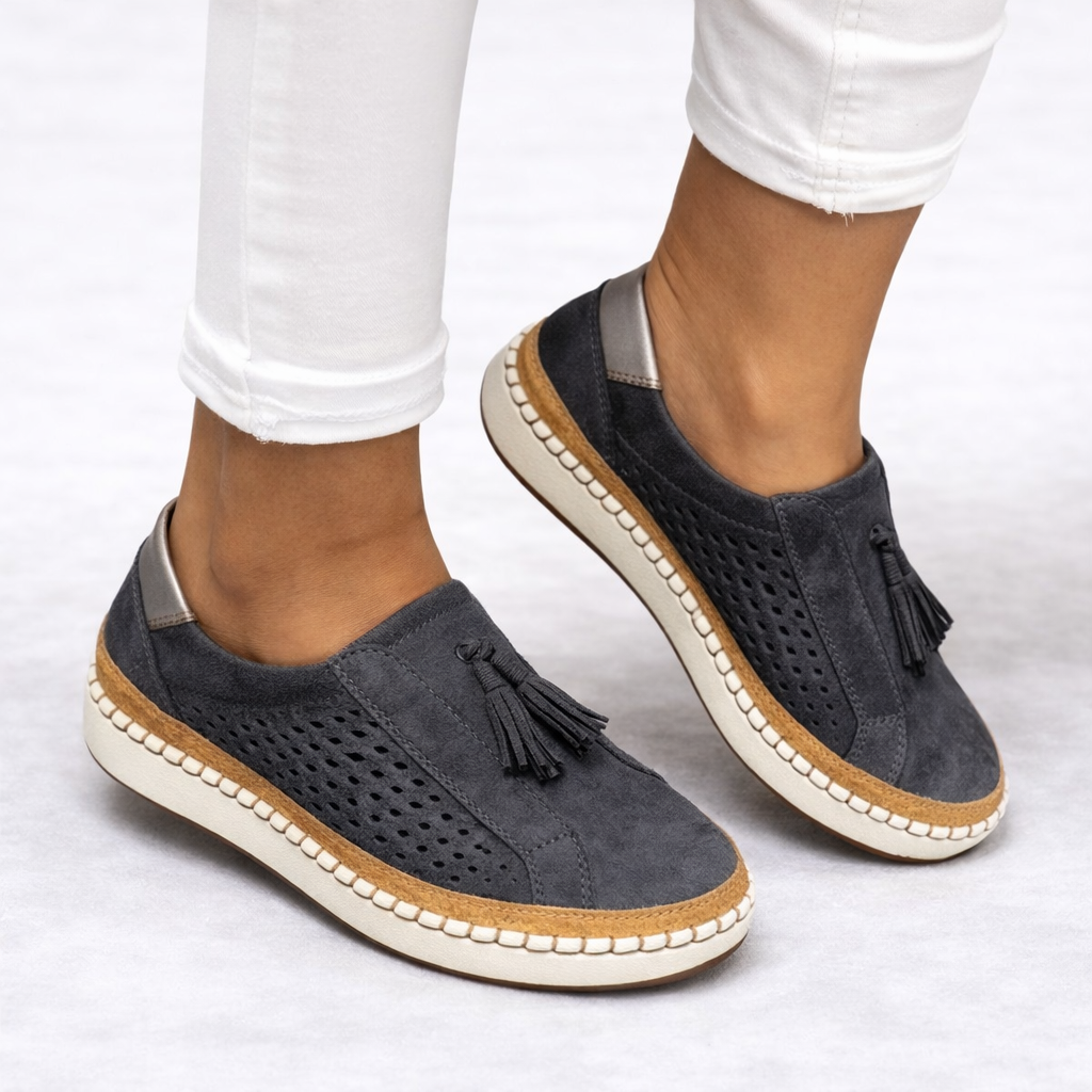 Orthopedic slip-on shoes in black with breathable perforated panels and tassel detail.