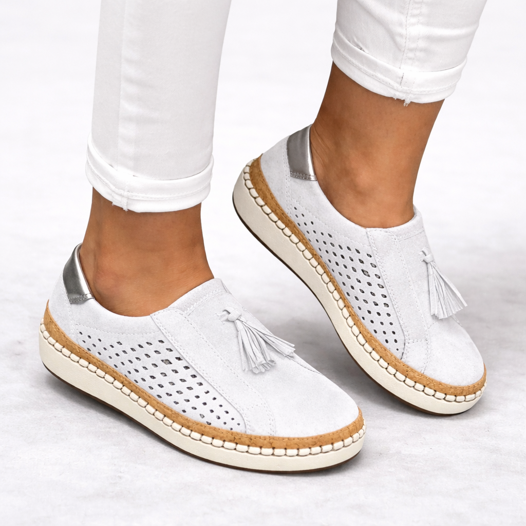 Orthopedic slip-on shoes in white with breathable perforated panels and tassel detail.
