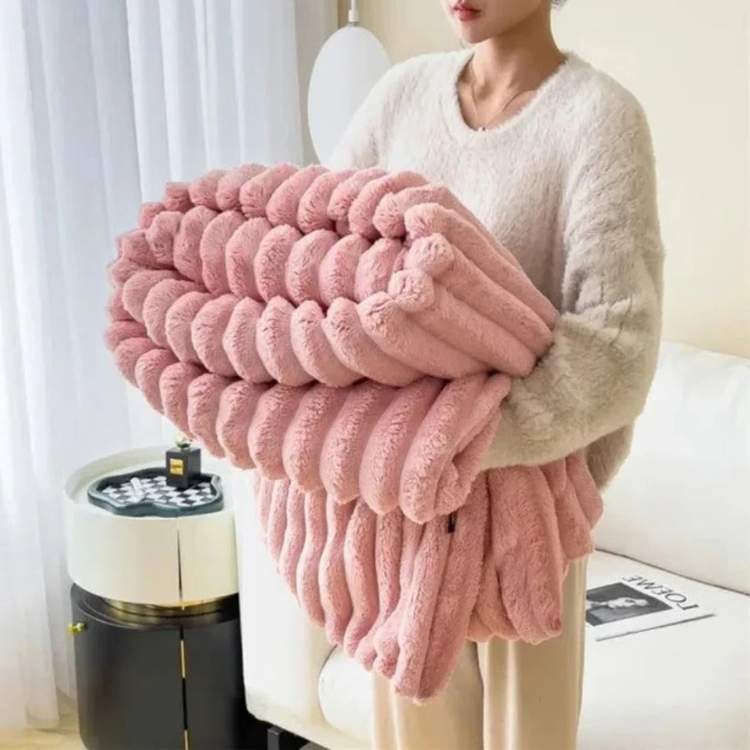 Faux-fur throw blanket in pink with a striped design, draped over a sofa