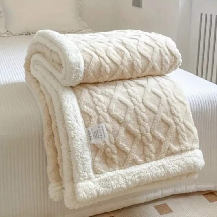 Sherpa weighted blanket in cream draped over a sofa
