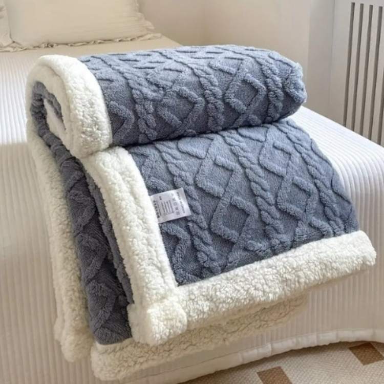 Sherpa weighted blanket in blue draped over a sofa